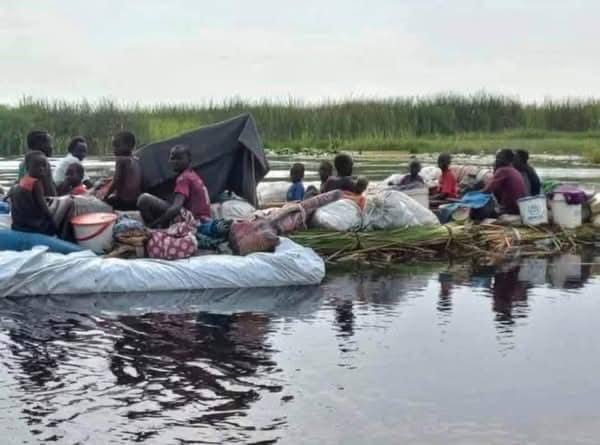 People and belongings move across water on a makeshift raft
