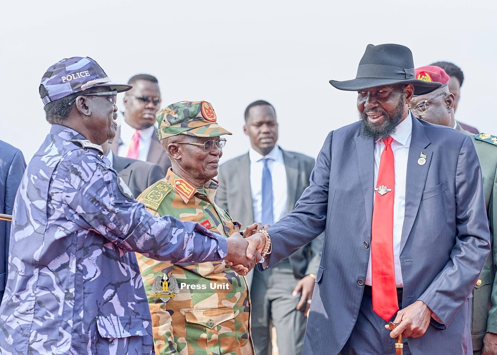 President Salva Kiir greets a police officer with security officials alongside him