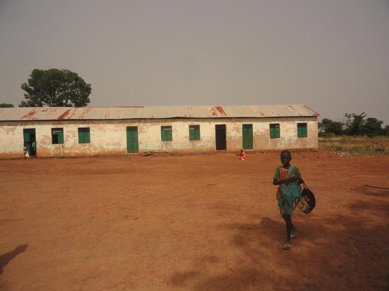 Child walking past a school building in a supplied photograph; location and date unverified